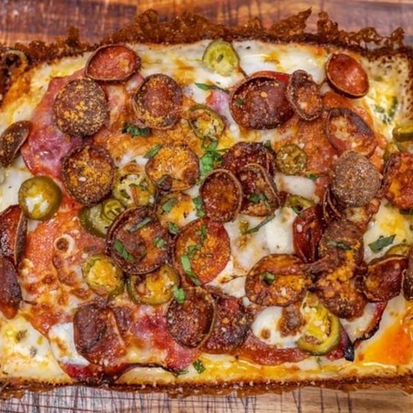 Close-up of a rectangular pizza with crispy pepperoni, jalapeños, and melted cheese.